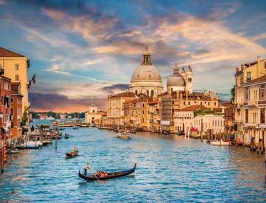 Traditional Gondola On Famous Canal Grande With Basilica Di Santa Maria Della Salute In Golden Evening Light At Sunset In Venice Italy 