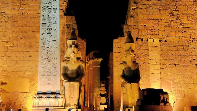 Illuminated Luxor Temple The Red Granite Obelisk And Two Seated Statues Of Ramesses Ii, Egypt