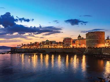 Night view of Alghero Torre Di Sulis from the water, Italy
