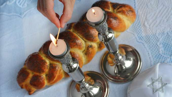 Womans Hand Lit Shabbath Candles With Uncovered Challah Bread And Kippah