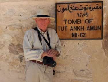 Man leaning against sign for Tomb of Tutankhamun