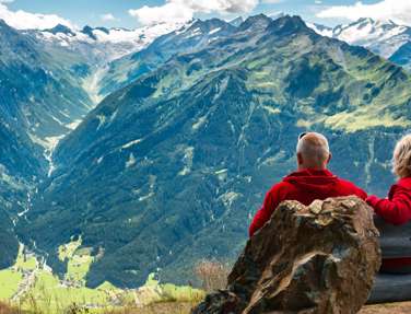 Couple sitting on bench overlooking mountains