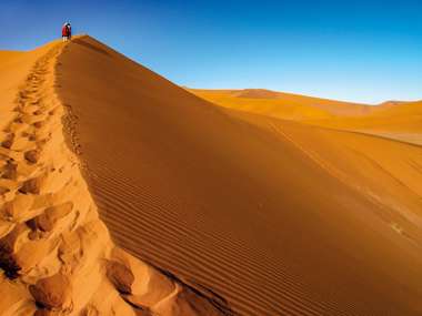 Tourist walking up a dune, Sossusvlei, Namib Nukluft National Park, Namibia